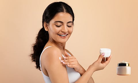 a girl applying face cream to her face