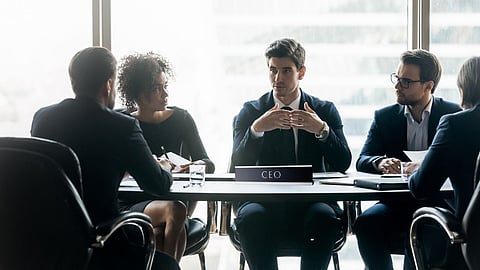 Business meeting with five people; CEO in center leading discussion