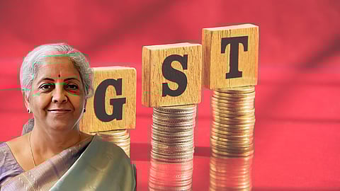 Indian Finance Minister Nirmala Sitharaman with wooden blocks spelling GST placed on stacks of coins, symbolising Goods and Services Tax revenue and policy