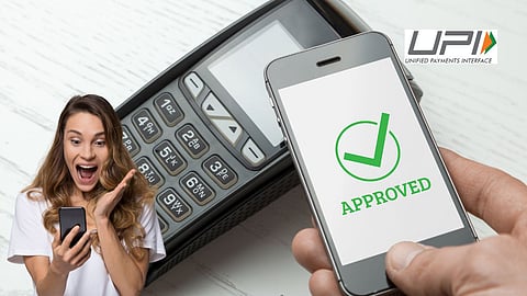 Excited woman holding a smartphone with UPI payment approval message displayed on screen, symbolizing successful digital transaction with a POS machine in the background