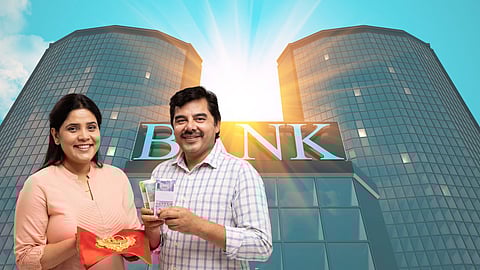A smiling man and woman standing in front of a modern bank building. The woman is holding a red pouch with gold jewellery, and the man is holding bundles of Indian currency notes, symbolising a gold loan transaction