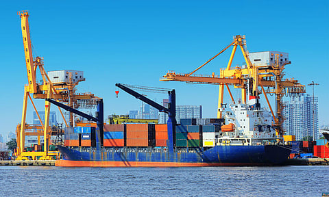 container cargo freight ship with working crane bridge in shipyard