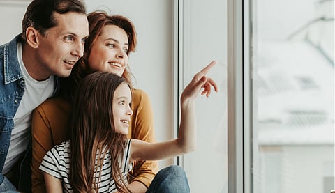 Happy family curiously looking at home window