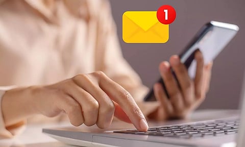 a women holding a mobile phone sitting in front of a laptop a sign of message