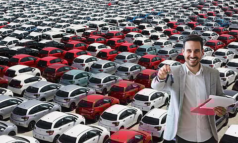 bunch of cars in a yard a sales man with car key