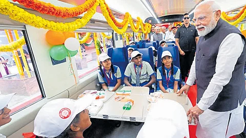 Prime Minister Narendra Modi interacts with school children on board the Vande Bharat express train at the KSR Bengaluru station on Sunday.