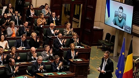 Belgium's Prime Minister Alexander De Croo, right, walks off the podium as Ukraine's President Volodymyr Zelenskyy watches from on screen, right, during a session of the plenary chamber at the Belgian Federal Parliament in Brussels, Belgium. (AP Photo/Virginia Mayo)