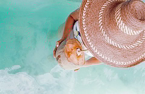 Drinking from a coconut on the beach by Chic Chateau, Haiti. Photo by Emily Bauman, unsplash