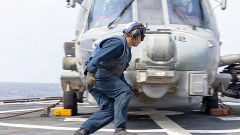 Um marinheiro norte-americano recolhe calços e correntes antes de um Seahawk levantar do USS Milius, contratorpedeiro destacado para a área de operações do Médio Oriente.