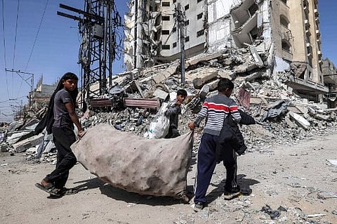 Um grupo de rapazes carrega um saco cheio de plástico que recolheram entre os destroços na cidade de Rafah.