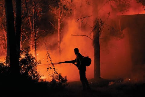 27 अगस्त 2021 को ग्रीस के उत्तरी एथेंस के जंगल में लगी आग को बुझाता दमकलकर्मी (फोटो: रॉयटर्स)