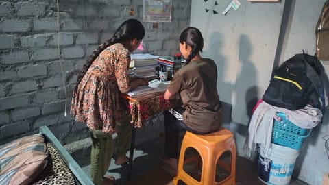 मध्यप्रदेश के इंदौर में चद्दर फैक्टी के कमरे में नर्सिंग प्रवेश परीक्षा की तैयारी करती कविता और रविता। फोटो: स्वाति शैवाल