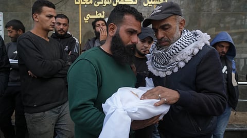 Palestinian Raed al-Khabba carries his 3-month-old daughter Mira al-Khabbaz, who was killed in an Israeli military strike, at Shifa Hospital in Gaza City
