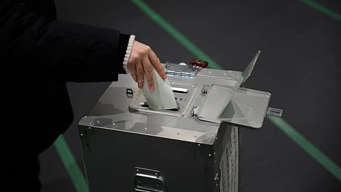 A voter fills in a ballot in the lower house election at a polling station