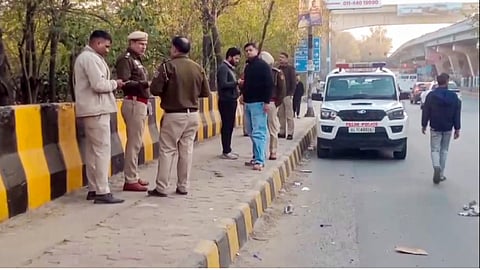 Police personnel investigate the spot after three people, including a woman, were found dead inside an abandoned car on the Peeragarhi flyover