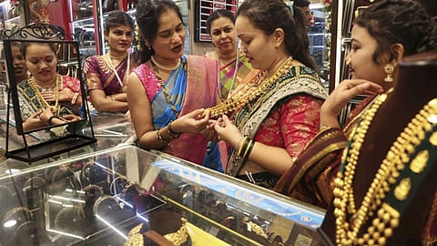 Image of a woman checking a gold chain at a jewelry showroom used for representative purpose
