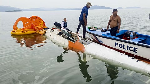 Police personnel inspect the wreckage of a Pawan Hans helicopter that made a controlled emergency landing in the sea near Mayabunder after developing a technical snag shortly after takeoff from Port Blair, in North and Middle Andaman district of the Andaman and Nicobar Islands.