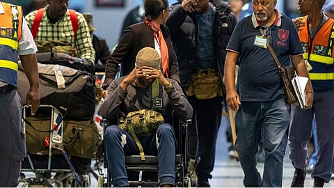South African men who were allegedly tricked into fighting for Russia in the war in Ukraine are escorted by police officers as they arrive at King Shaka International Airport in Durban, South Africa