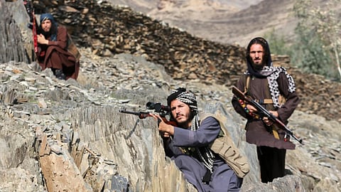 Afghan Taliban soldiers look toward the Pakistani side, with one peering through the sight of his rifle, on the Afghan side of the Torkham border crossing with Pakistan in Torkham, Afghanistan