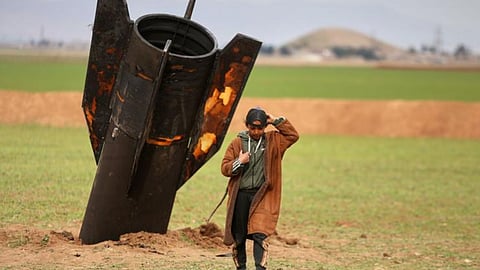A shepherd boy walks away from an unexploded Iranian projectile that landed in an open field in the outskirts of Qamishli, eastern Syria