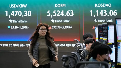 A currency trader passes by a screen showing the Korea Composite Stock Price Index (KOSPI), rear center, and the foreign exchange rate between U.S. dollar and South Korean won, rear left, at the foreign exchange dealing room of the Hana Bank headquarters in Seoul, South Korea.