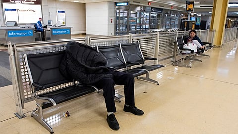 A man sleeps in the baggage claim area of Ronald Reagan National Airport, in Arlington, Va