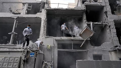 Volunteers clean debris from a residential building damaged when a nearby police station was hit Friday in a US-Israeli strike in Tehran, Iran