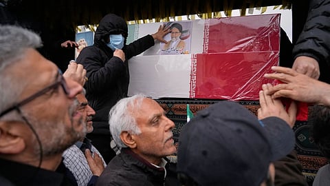 Iranians reach toward the coffins as they follow the funeral procession of Iran’s intelligence minister Esmail Khatib and, according to Iranian officials, his wife and daughter, in Tehran, Iran
