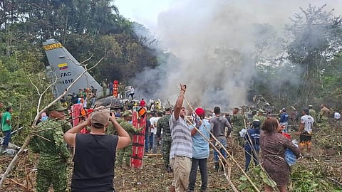 People stand around a military cargo plane that crashed after taking off from Puerto Leguizamo, Colombia, a remote municipality in the Amazonian province of Putumayo, Monday, March 23, 2026.