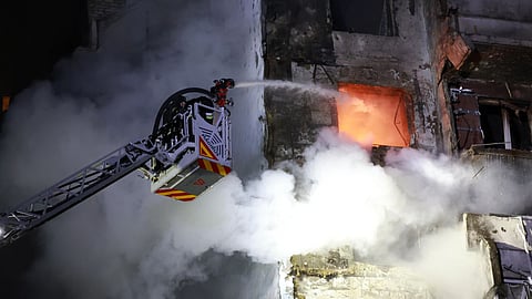 Rescue workers try to put out a fire of a residential building burning after a Russian drone attack on Zaporizhzhia, Ukraine