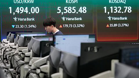 A currency trader watches monitors near a screen showing the Korea Composite Stock Price Index (KOSPI), top center, and the foreign exchange rate between U.S. dollar and South Korean won, top center left, at the foreign exchange dealing room of the Hana Bank headquarters in Seoul, South Korea, Tuesday, March 24, 2026.