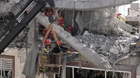 First responders work to remove a body from the rubble of a residential building hit in an overnight U.S.-Israeli strike in Tehran