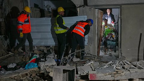 Residents carry personal belongings as they leave a building damaged in a missile strike in Tel Aviv, Israel