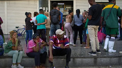 People wait their turn to enter a bank in Havana, Cuba