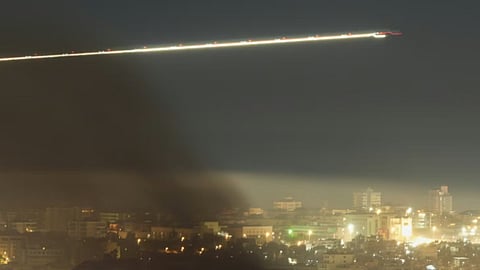 A Middle East Airlines plane flies as smoke rises from Israeli airstrikes in Beirut, Lebanon, in March 2026