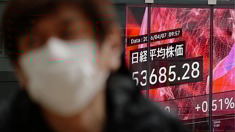 A person walks in front of an electronic stock board showing Japan's Nikkei index at a securities firm Tuesday, April 7, 2026, in Tokyo.