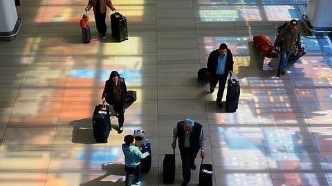 Stained-glass windows cast colorful shadows on the floor as travelers walk through LaGuardia Airport in New York