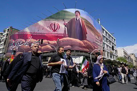 Government supporters walk past a billboard depicting Iran’s Supreme Leader Mojtaba Khamenei as they gather to mark the 40th day since the killing of his father, slain Supreme Leader Ayatollah Ali Khamenei, in Tehran, Iran,