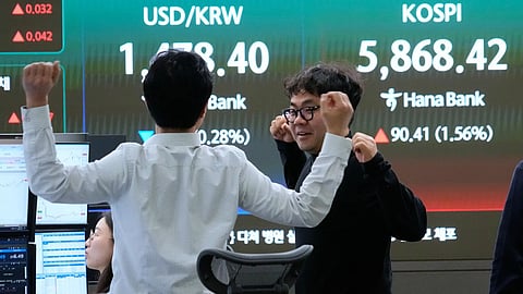 Currency traders stretch near a screen showing the Korea Composite Stock Price Index (KOSPI), right, and the foreign exchange rate between U.S. dollar and South Korean won at the foreign exchange dealing room of the Hana Bank headquarters, in Seoul, South Korea, Friday, April 10, 2026.