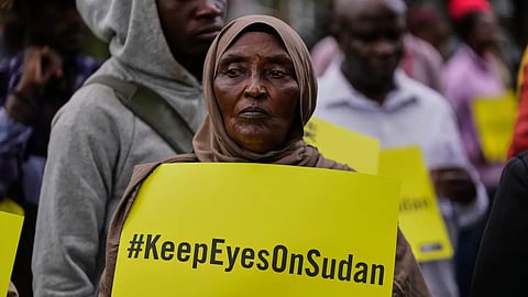 A woman holds a placard during a tree planting event commemorating the war in Sudan as it enters its fourth year, in Nairobi, Kenya