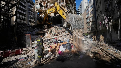 A Lebanese civil defense worker looks on as an excavator operates on the rubble of a building destroyed in an Israeli airstrike a day earlier in Beirut, Lebanon