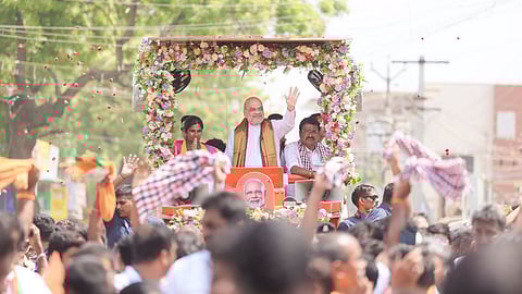 Union Home Minister Amit Shah waves to a gathering during a roadshow ahead of Tamil Nadu Assembly elections, in Erode, Tamil Nadu
