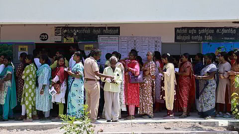 Voters stand in a queue outside a polling booth, waiting patiently to cast their votes.