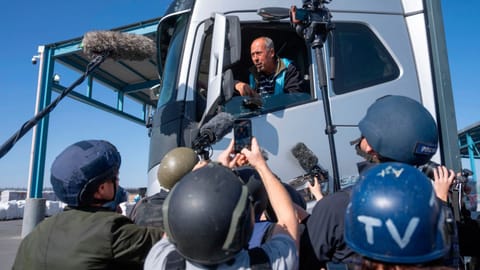 A truck driver picks up humanitarian aid designated for Gaza, as reporters tour the Palestinian side of the Kerem Shalom crossing where aid is awaiting pickup