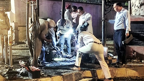 Security personnel inspect the remains of a scooter after a fire incident near the BSF headquarters, in Jalandhar