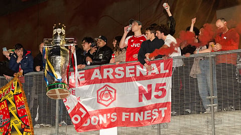 Arsenal fans celebrate with a miniature Premier League trophy