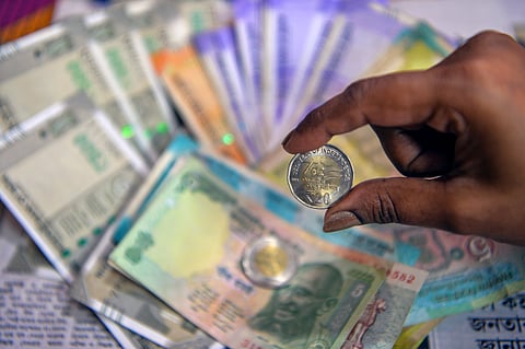 Siliguri: A woman displays a Rs 20 coin along with Indian currency notes amid market fluctuations following India-US trade developments, in Siliguri, Tuesday,