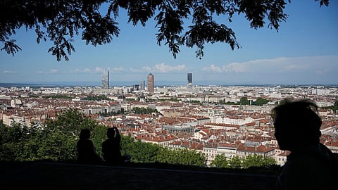 People shelter under the shadow of a tree during a heat wave, in Lyon, central France