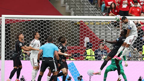 Qatar's Boualem Khoukhi (16) heads the ball over Canada's Tani Oluwaseyi (12) during the World Cup Group B