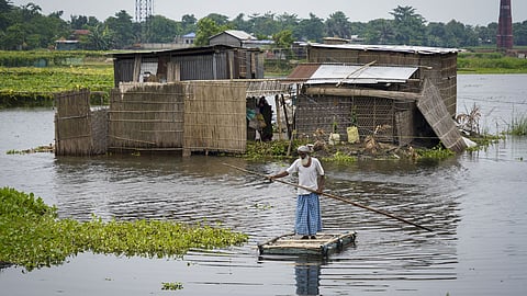 A man uses a makeshift raft to travel through floodwaters, in Morigaon district, Assam